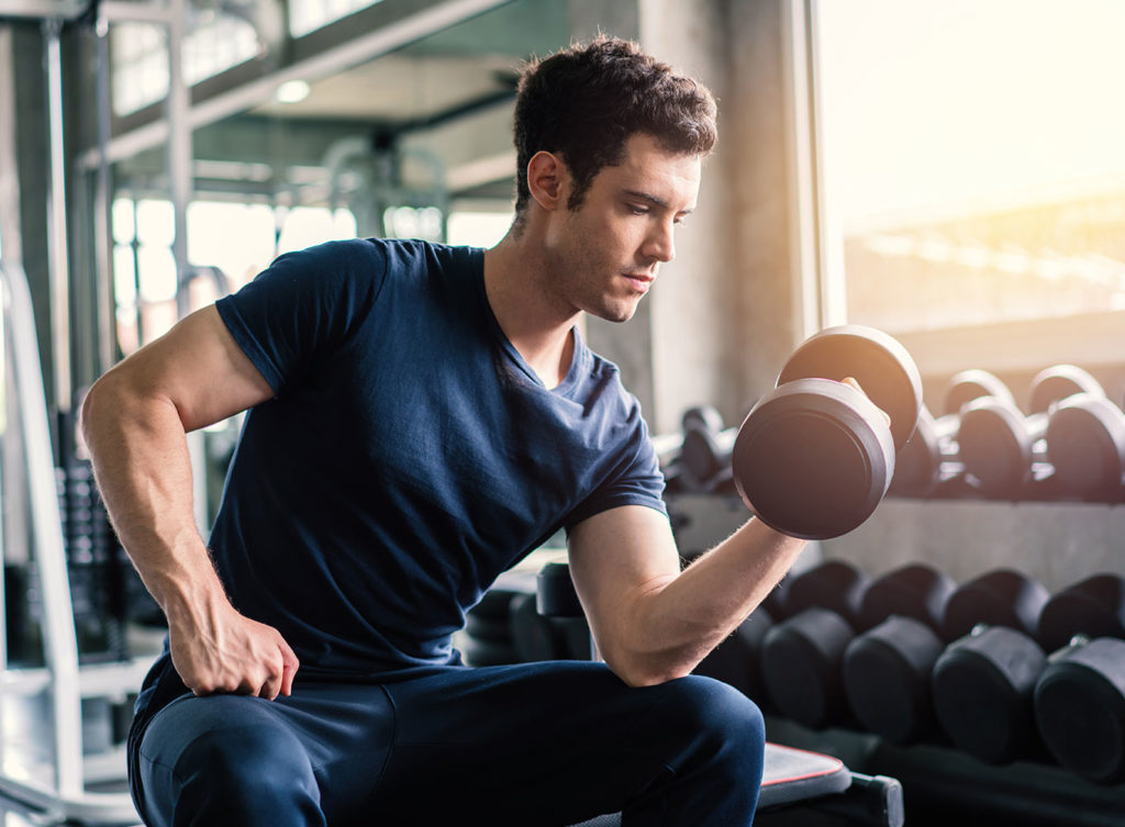 young man lifting weights indicating men's health and wellness dallas tx