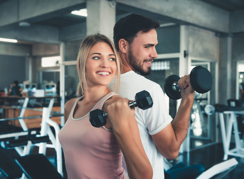 young man and woman lifting weights to promote weight loss in dallas texas