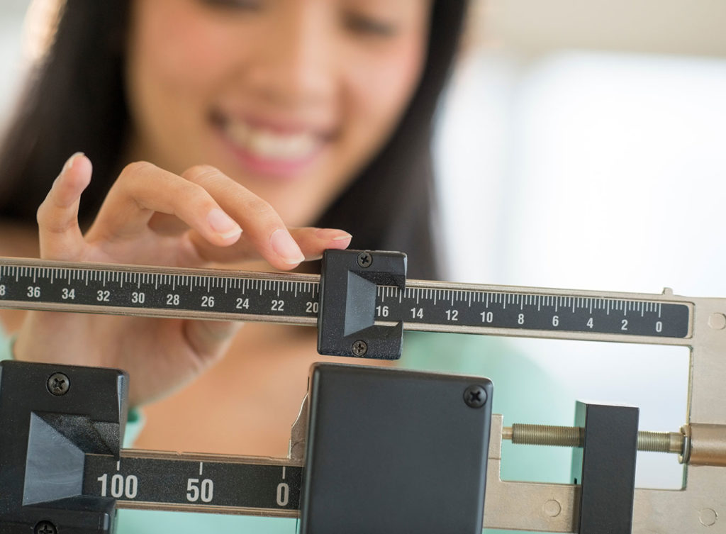 asian woman weighing herself to see the results of taking phentermine dallas texas