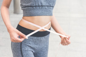 A person holding a measuring tape around their waist to measure weight loss that has been effective with semaglutide from Simply Direct Medicine in Dallas, TX.