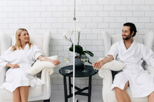 A young couple sits in separate white chairs with their arms extended and smiling as they receive vitamin IV infusion therapy at a modern wellness center in Fort Worth, TX.