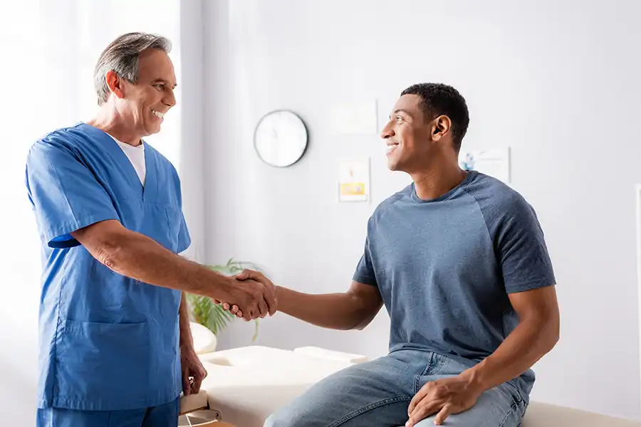 Simply Direct Medicine—A doctor shakes hands with a male patient in his medical office in Farmers Branch, TX.