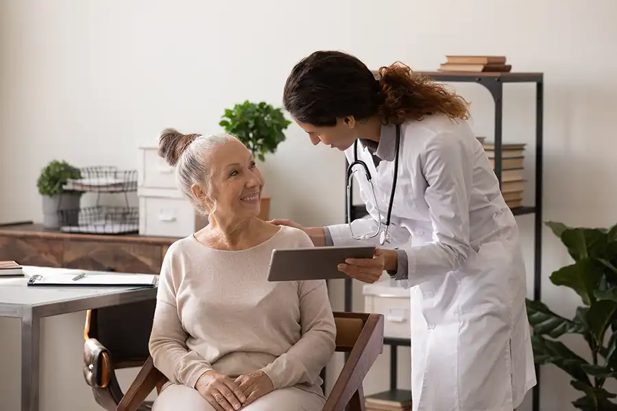 Simply Direct Medicine—A female doctor explains menopause to an older female patient in her medical office in Farmers Branch, TX.